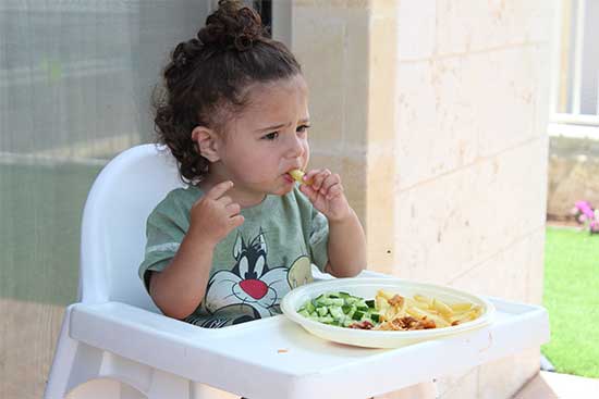 kid eathing nutritious food and not happy about it