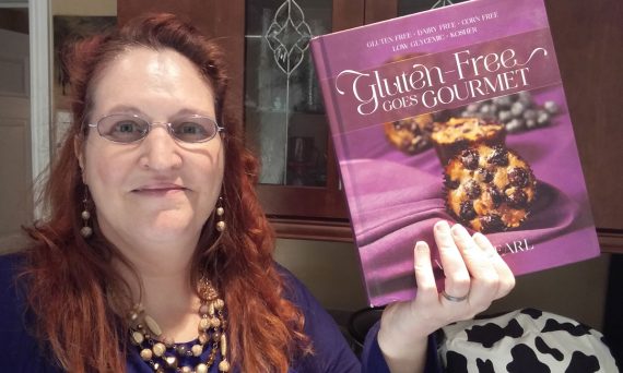 Carma holding a copy of Gluten-Free Goes Gourmet