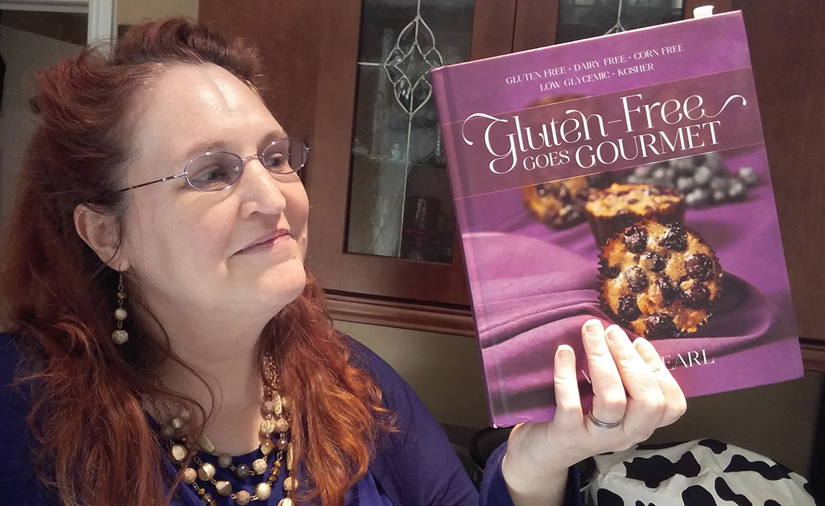 Carma holding a copy of Gluten-Free Goes Gourmet