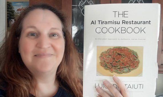 Carma Spence holding a copy of The Al Tiramisu Restaurant Cookbook