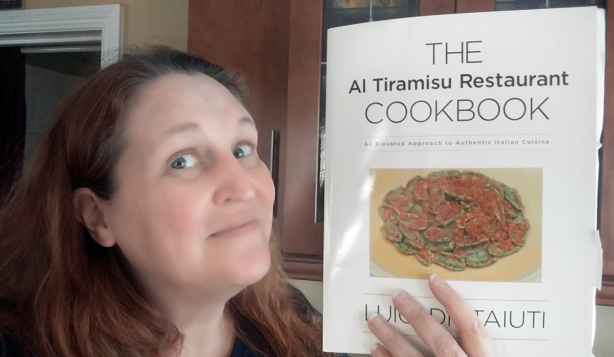 Carma Spence holding a copy of The Al Tiramisu Restaurant Cookbook